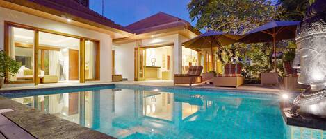 Una piscina al aire libre, sombrillas, sillones reclinables de piscina