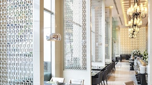 Un restaurant moderne doté d’une grande salle à manger, de hauts plafonds et de panneaux décoratifs en treillis.