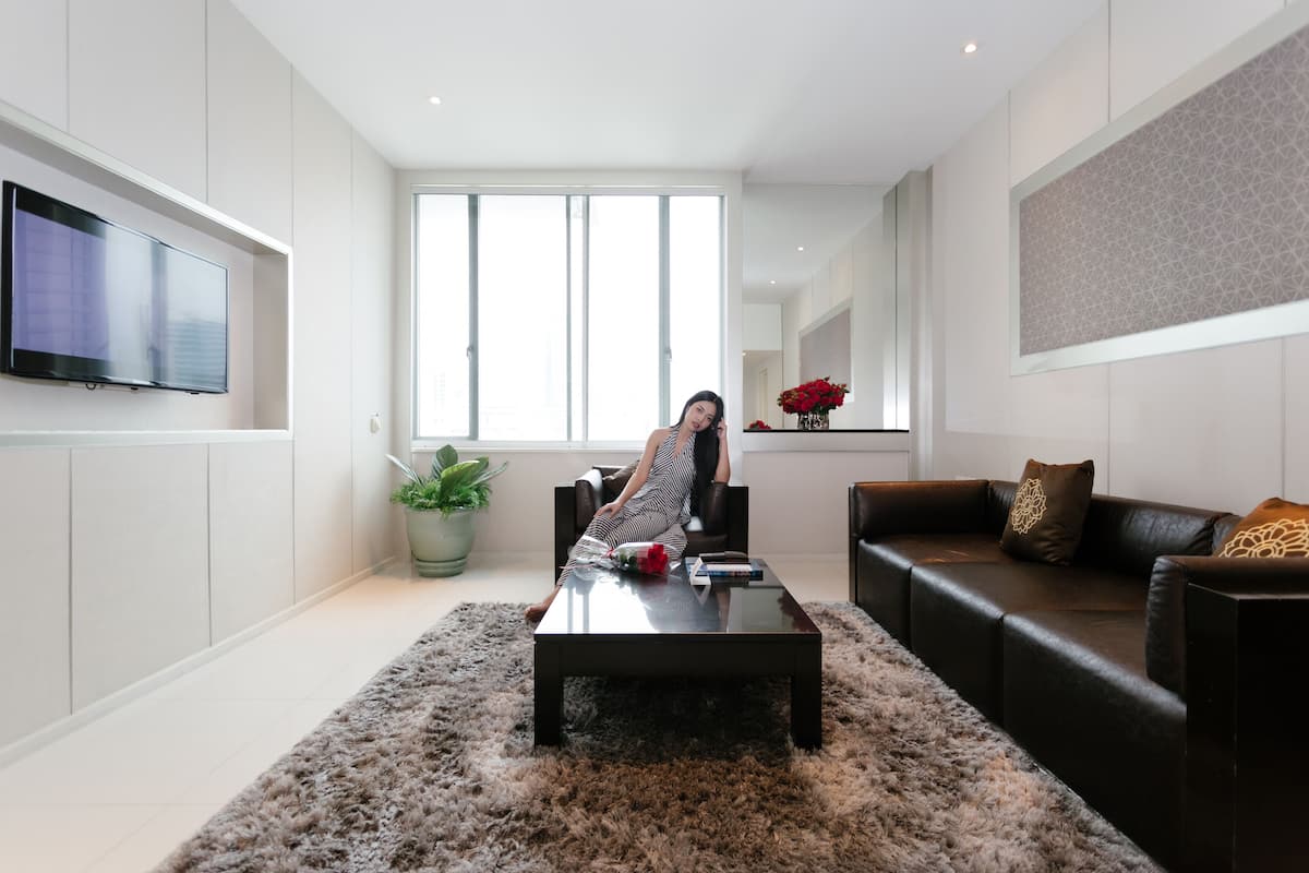 Een moderne woonkamer met een groot raam, een flatscreen televisie aan de muur, een leren bank en een salontafel.