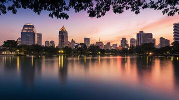 Un horizonte urbano al atardecer, con edificios reflejados en aguas tranquilas.