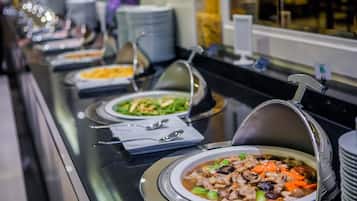 Un bufé con diversos platos, incluyendo un bol de sopa con verduras y carne, y otros platos al fondo.