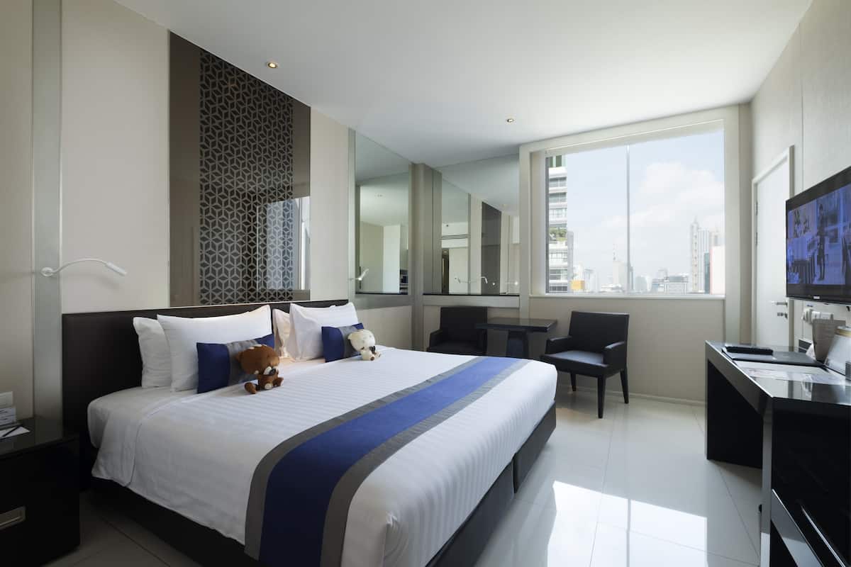 Een moderne hotelkamer met een groot bed, een bureau, een stoel en een televisie.