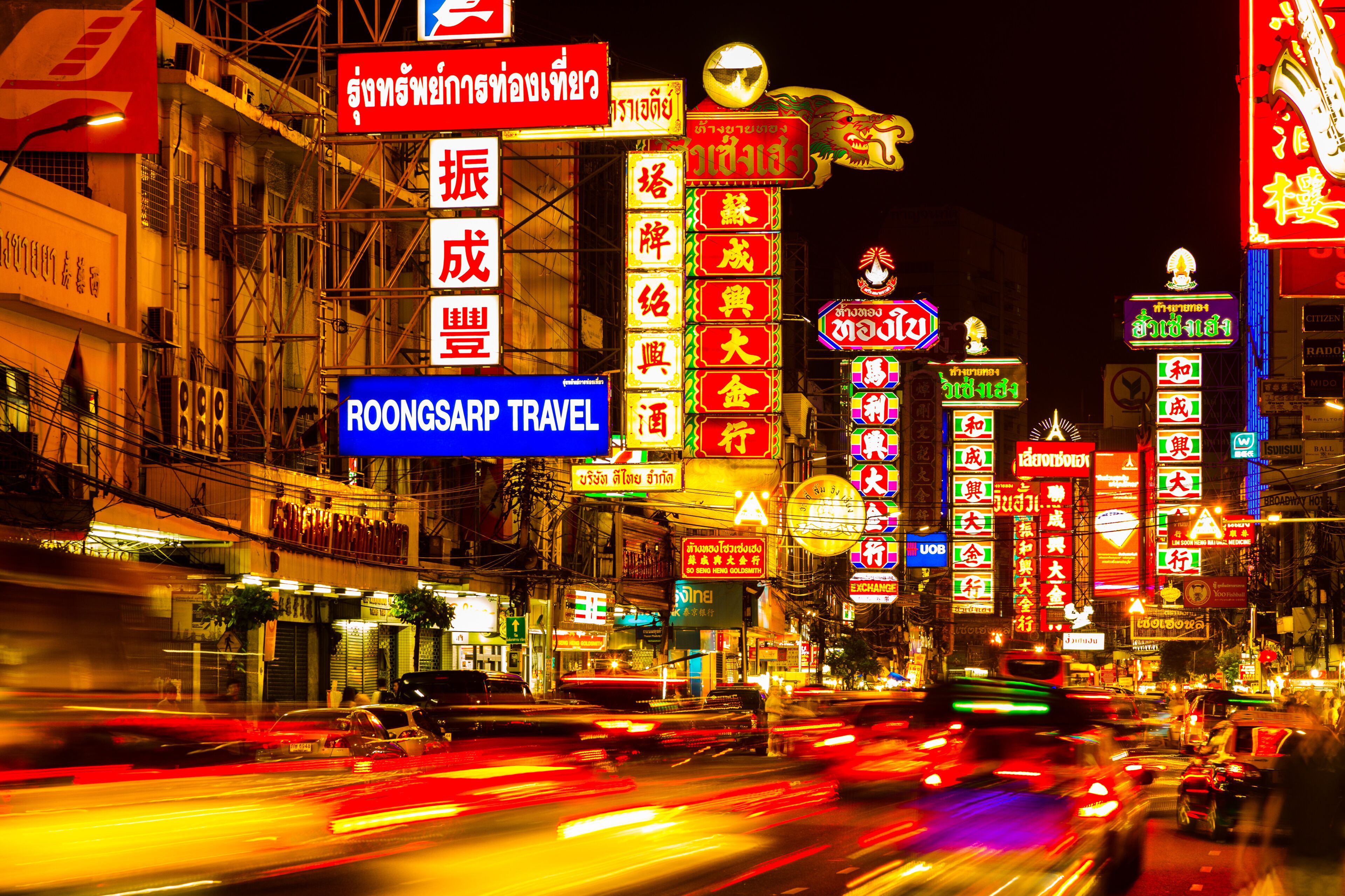 A busy street at night with neon signs and traffic.