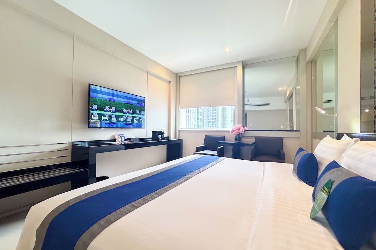 Een moderne hotelkamer met een groot bed, een bureau, een flatscreen televisie en een raam met zonwering.