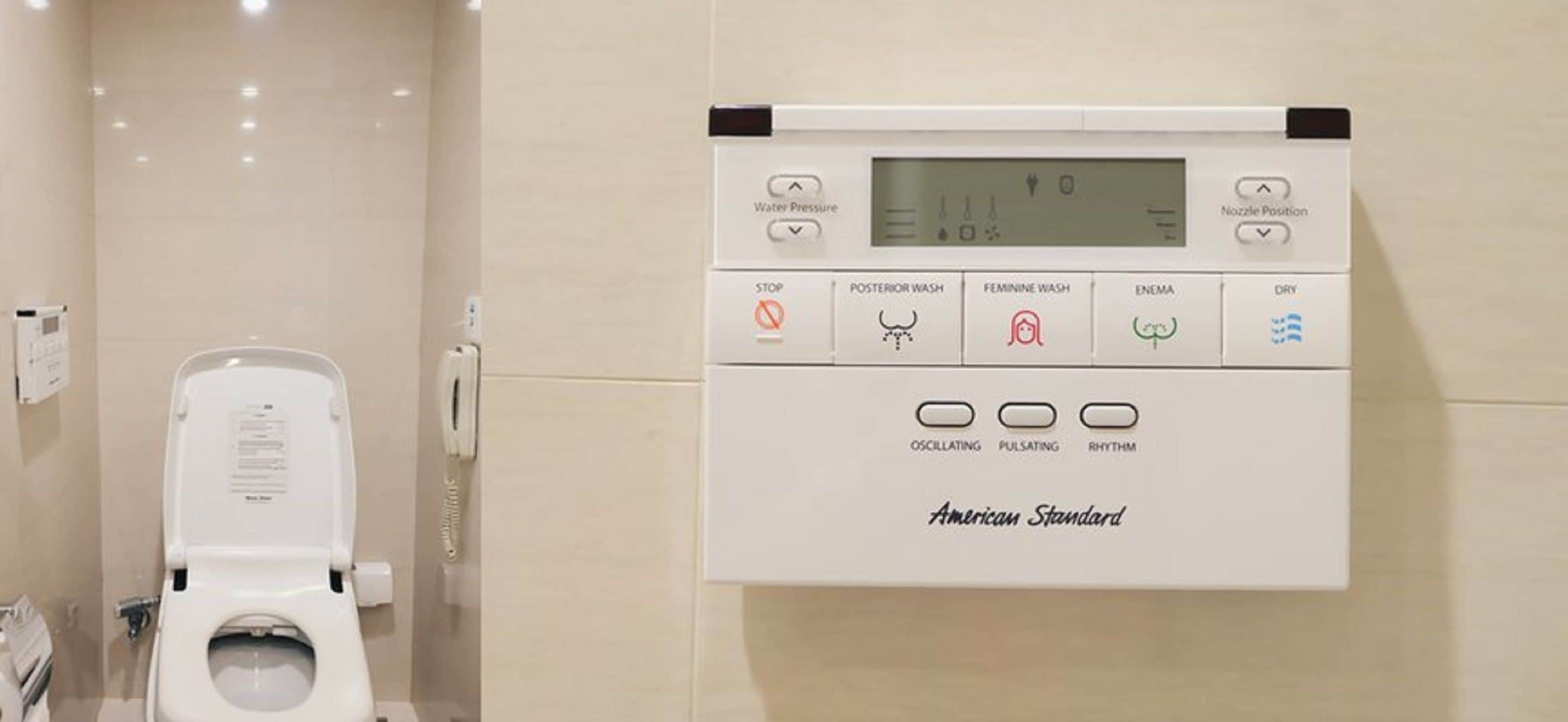 Un baño moderno con inodoro y un panel de control en la pared para la presión del agua, tipos de lavado y configuraciones.