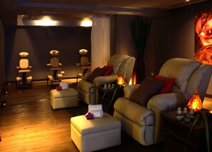 A massage room with three reclining chairs, a small table with candles, and a wooden floor.