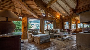A spacious log cabin interior with a large window offering a view of the outdoors. - Zannier Le Chalet (Megeve)