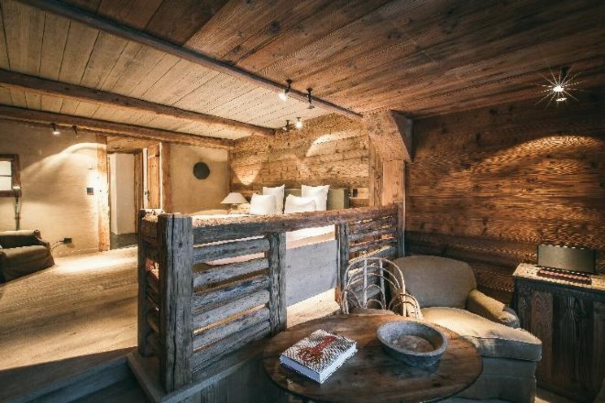 Una habitación rústica de madera con una cama, una silla, una mesa y una chimenea.