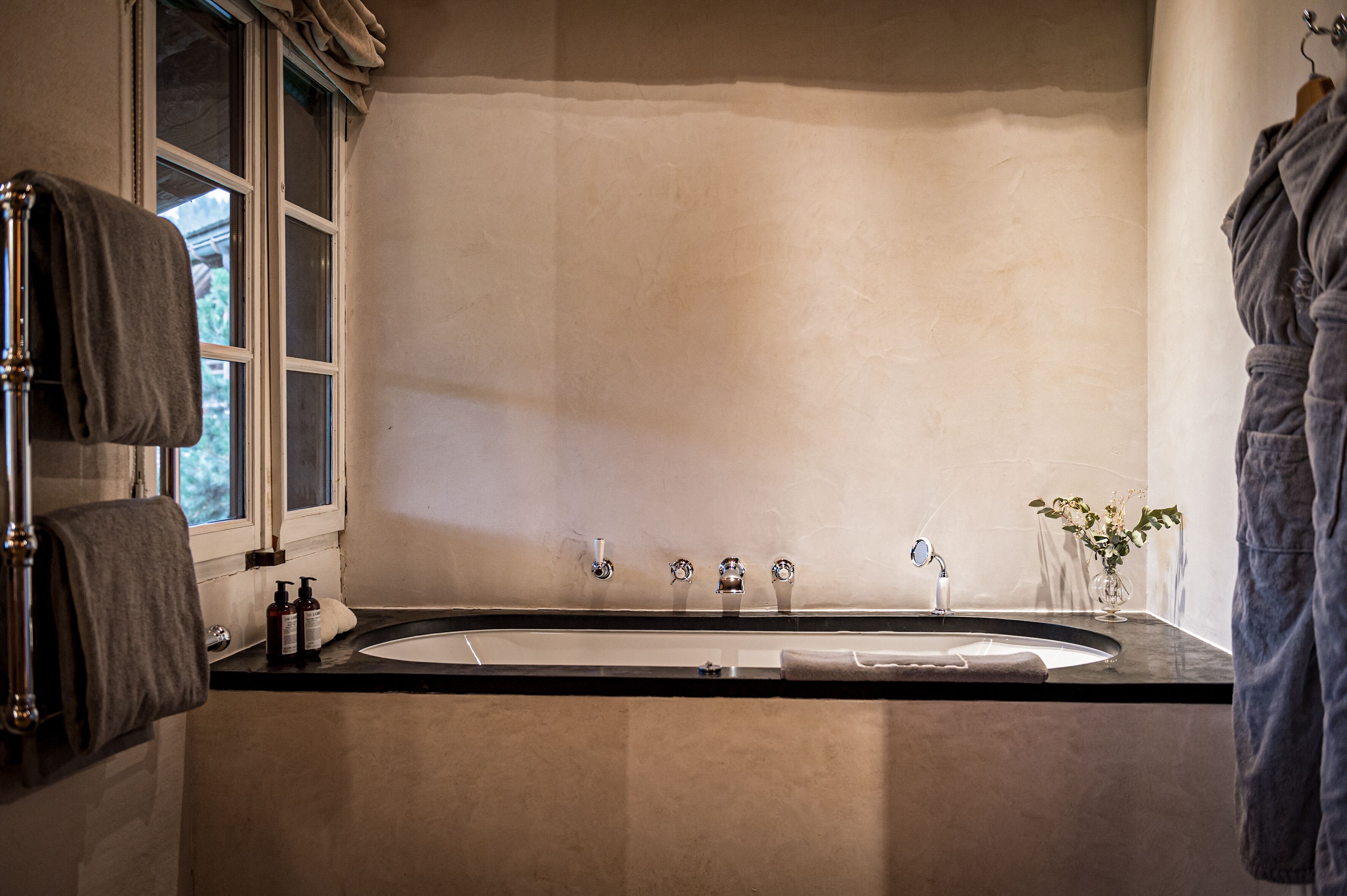 Un bagno con una vasca, una finestra e un portascopevoli.