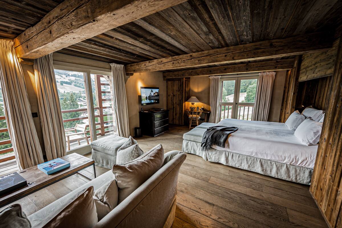 Una habitación acogedora con cama, sofá, televisión y escritorio con un libro.