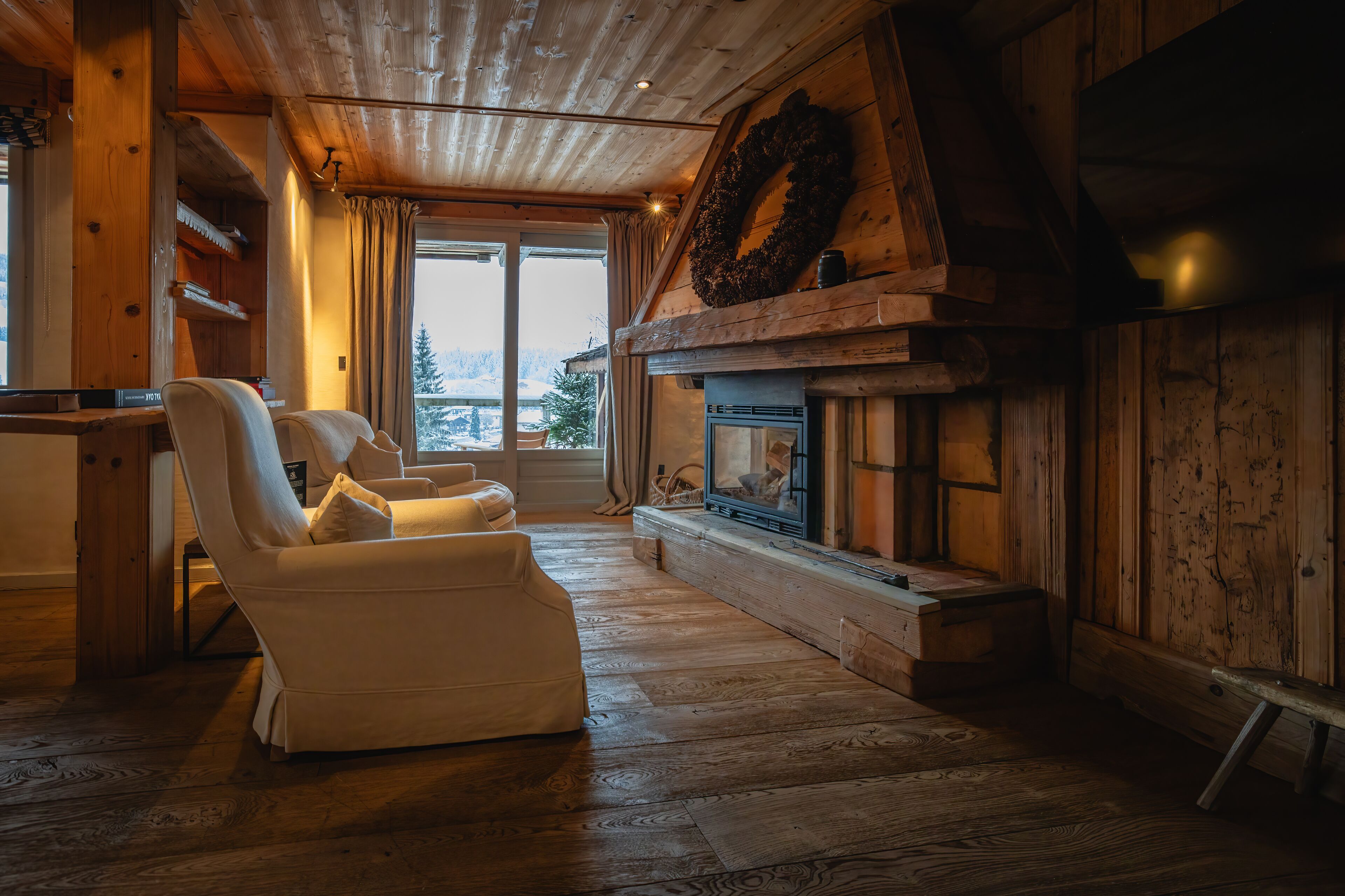Una sala de estar acogedora con chimenea, paredes de madera y vistas al exterior.