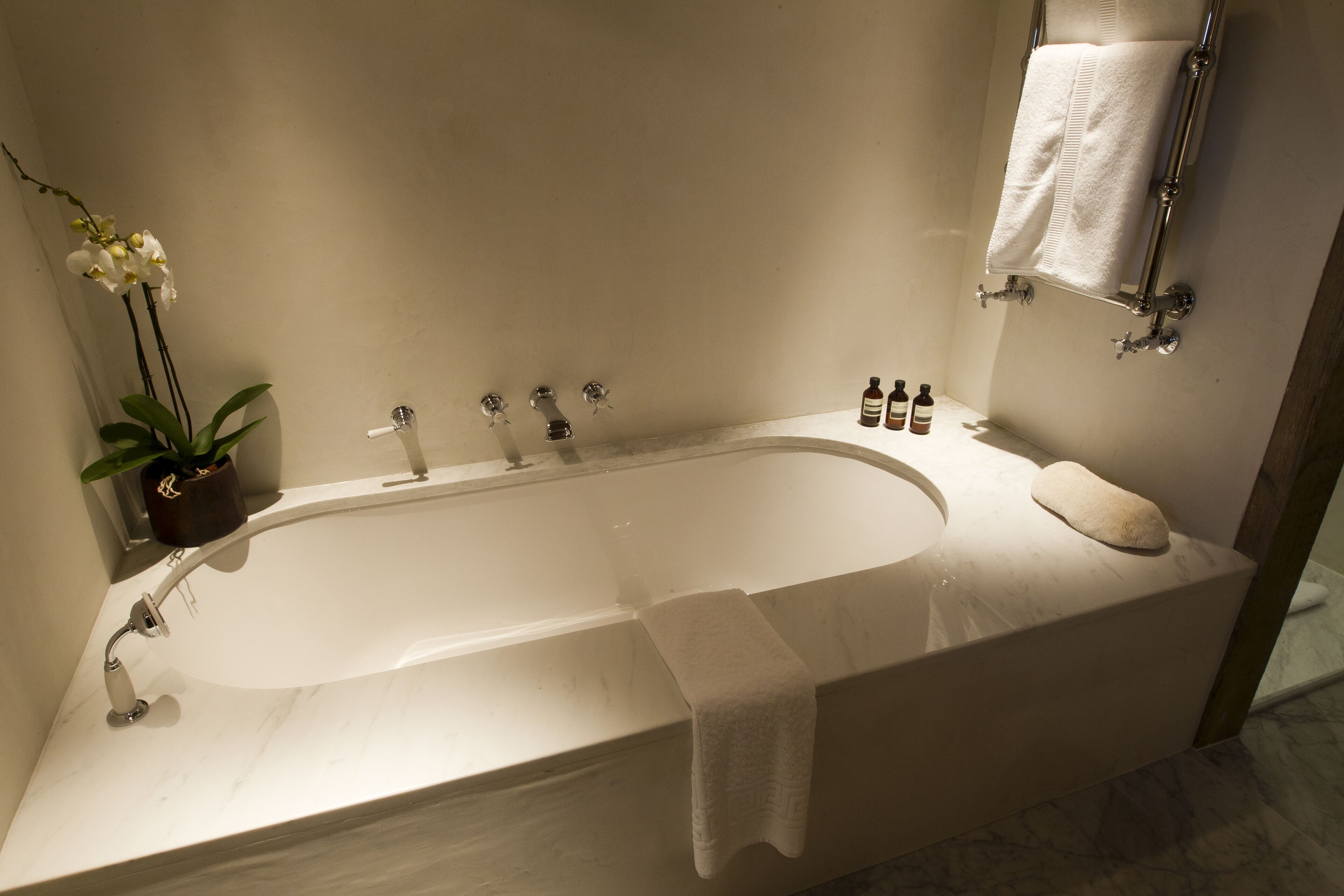 A modern bathroom with a freestanding bathtub, a potted orchid, and a towel rack.