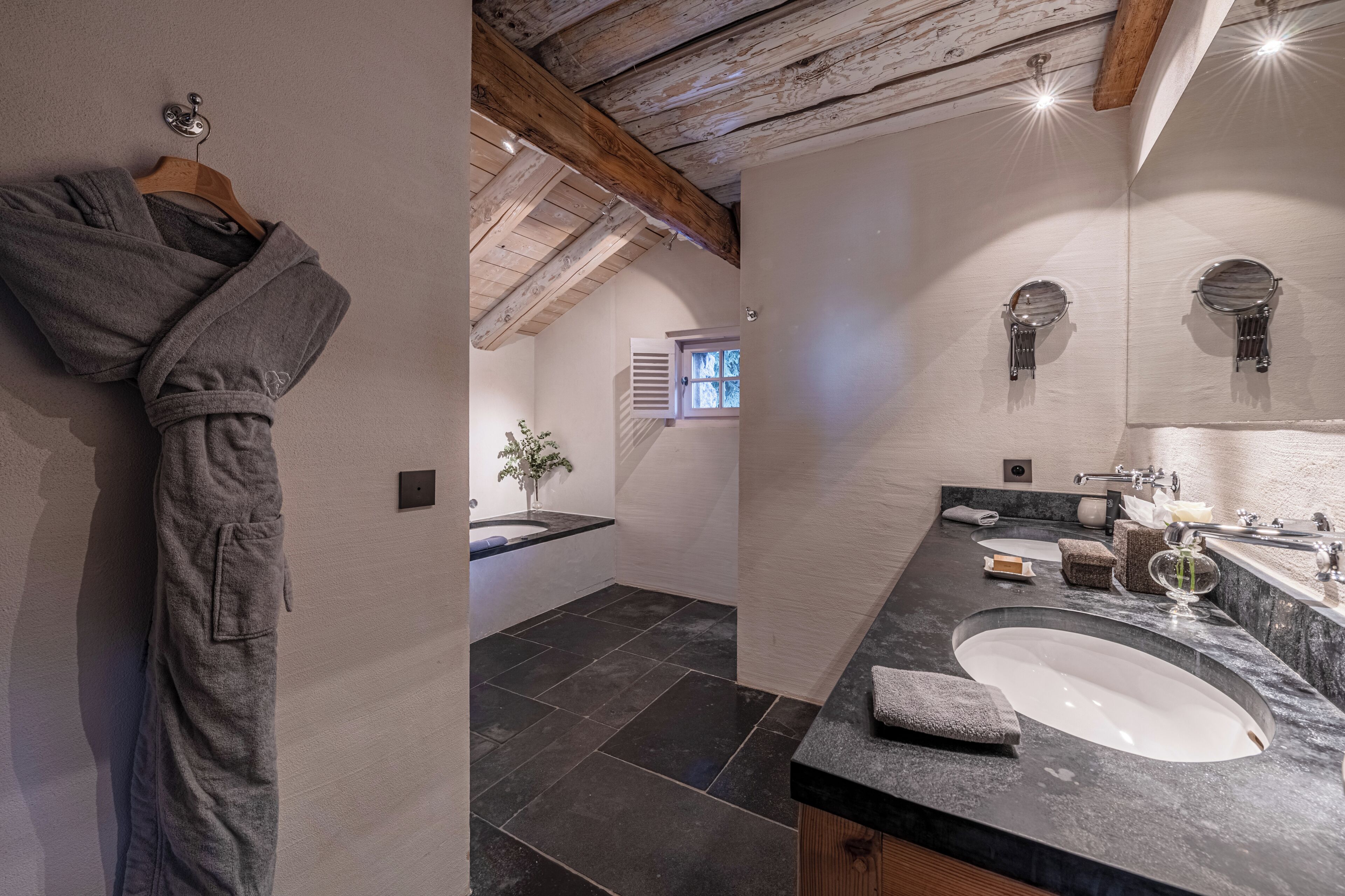 Une salle de bain moderne avec un grand lavabo, un miroir et un peignoir suspendu à un porte-serviettes.