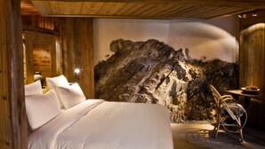 Un dormitorio con una cama grande, paredes de madera y un mural de pared de roca.