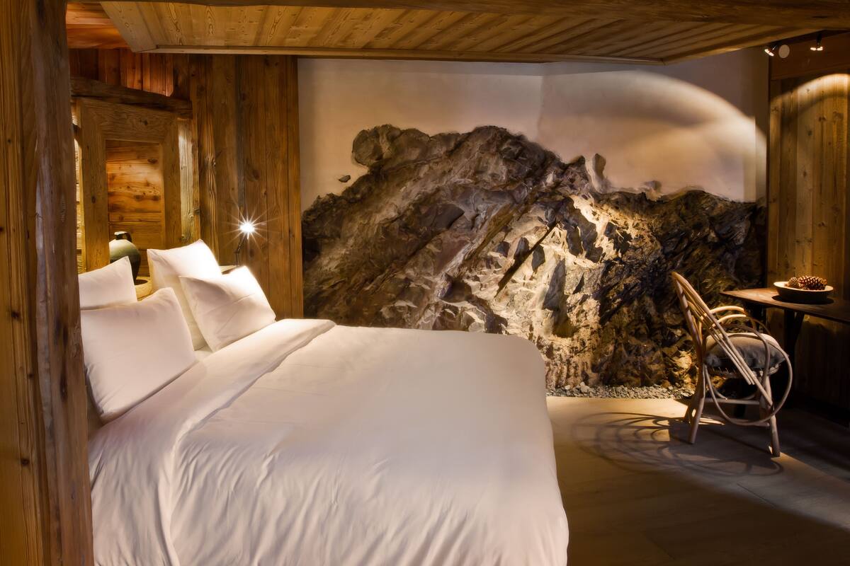 Un dormitorio con una cama grande, paredes de madera y un mural de pared de roca.