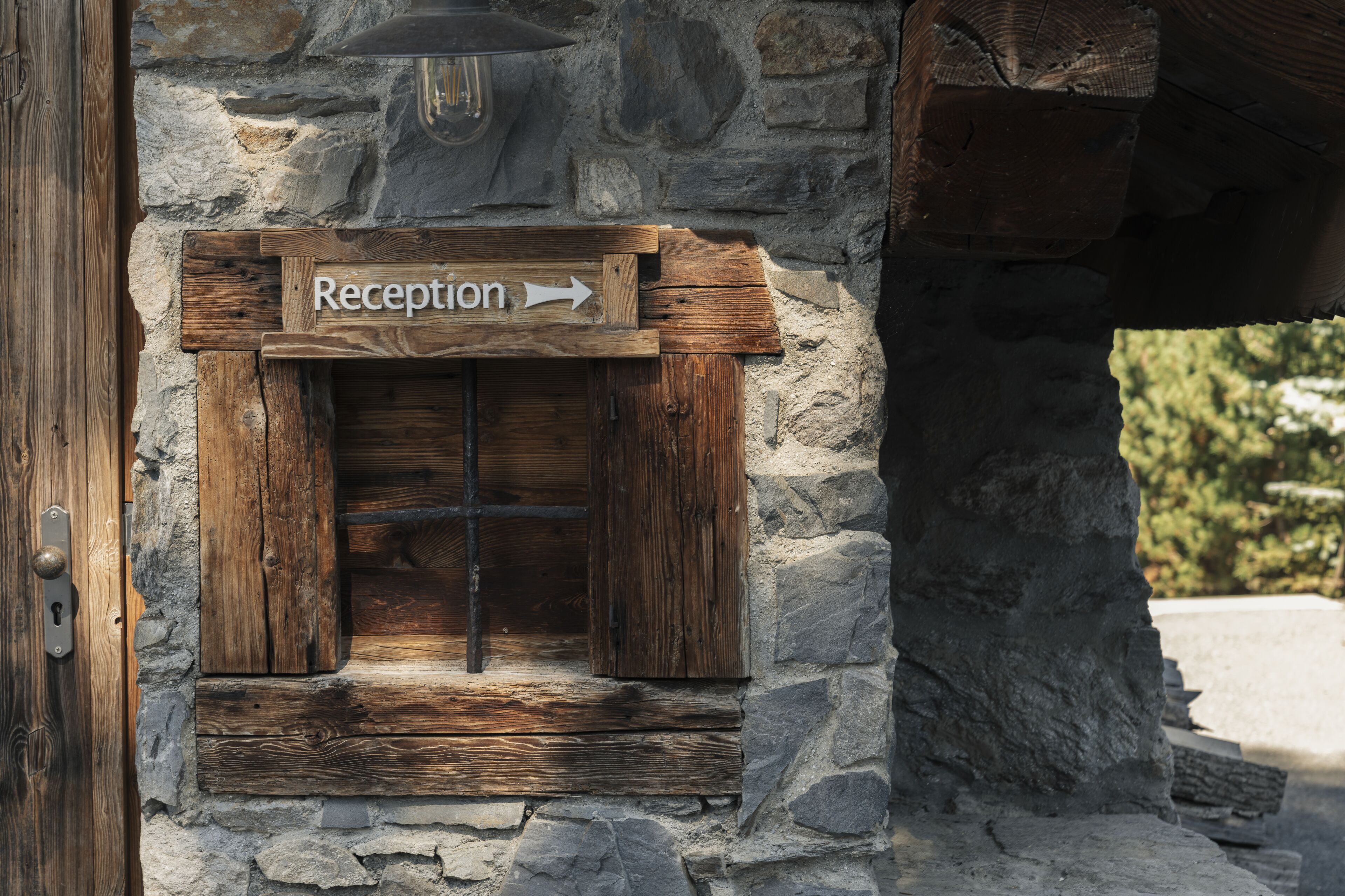 A rustic reception sign with an arrow pointing to the right, set in a stone wall with wooden elements.