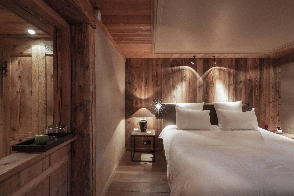 Una habitación de madera con una cama, una mesita de noche y un espejo.