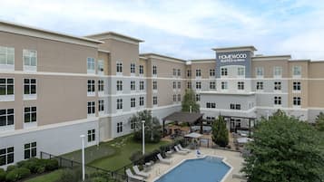 A multi-story hotel with a pool area, outdoor seating, and a covered patio.