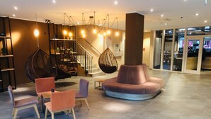 A modern lobby with a round seating area, a staircase, and hanging chairs. - Adesso Hotel Göttingen (Goettingen)