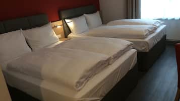 A hotel room with two beds, each with white linens and a headboard. There is a nightstand with a lamp between the beds.
