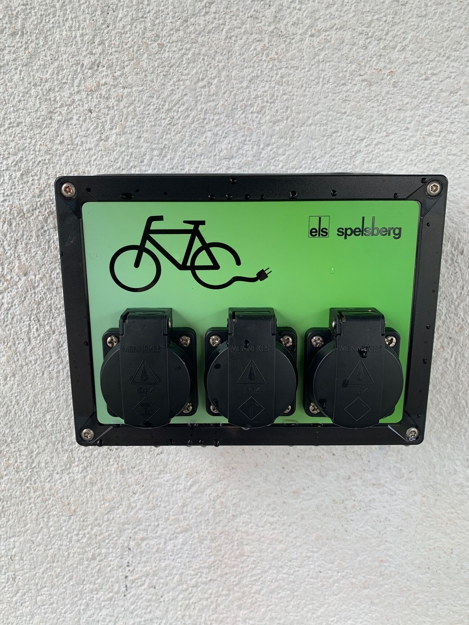 A green electrical box with a bicycle symbol and three black plugs.