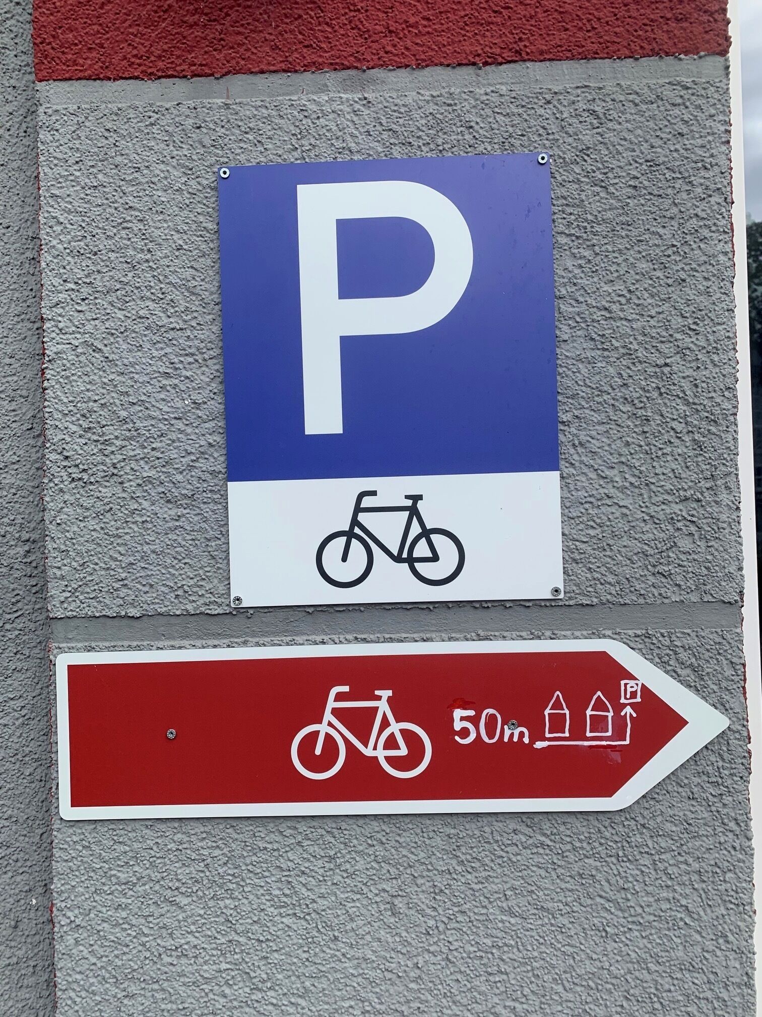 Señal de estacionamiento con símbolo de bicicleta e indicador direccional que muestra una distancia de 50 metros.
