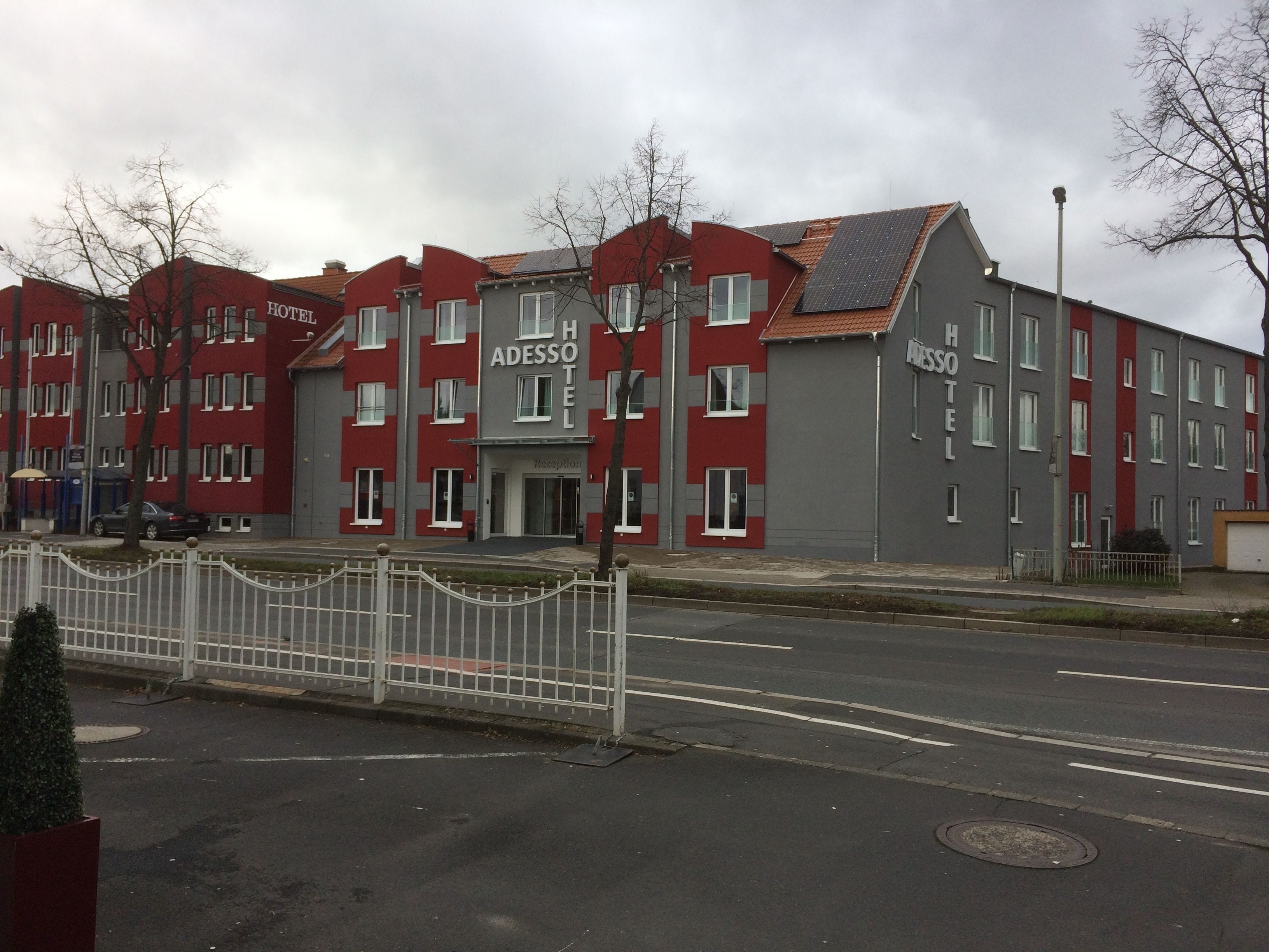 A hotel with a red and grey facade, multiple windows, and a reception area.