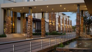 A modern hotel entrance with stone pillars, a covered walkway, and a small water feature. - Premier Hotel Midrand (Midrand)