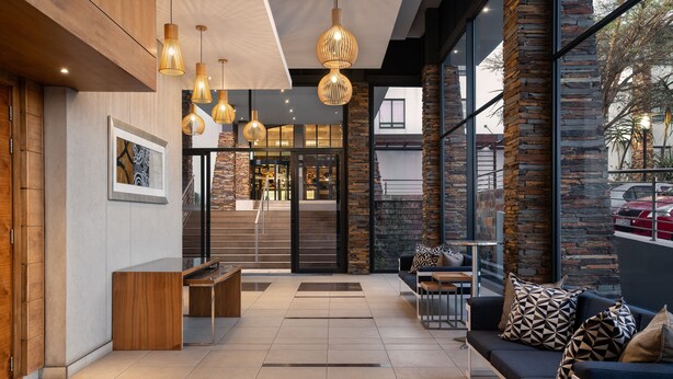 A modern lobby with a reception desk, seating area, and large windows offering views of the outside. - Premier Hotel Midrand (Midrand)