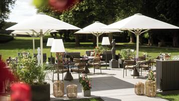 An outdoor patio area with seating, umbrellas, and potted plants.