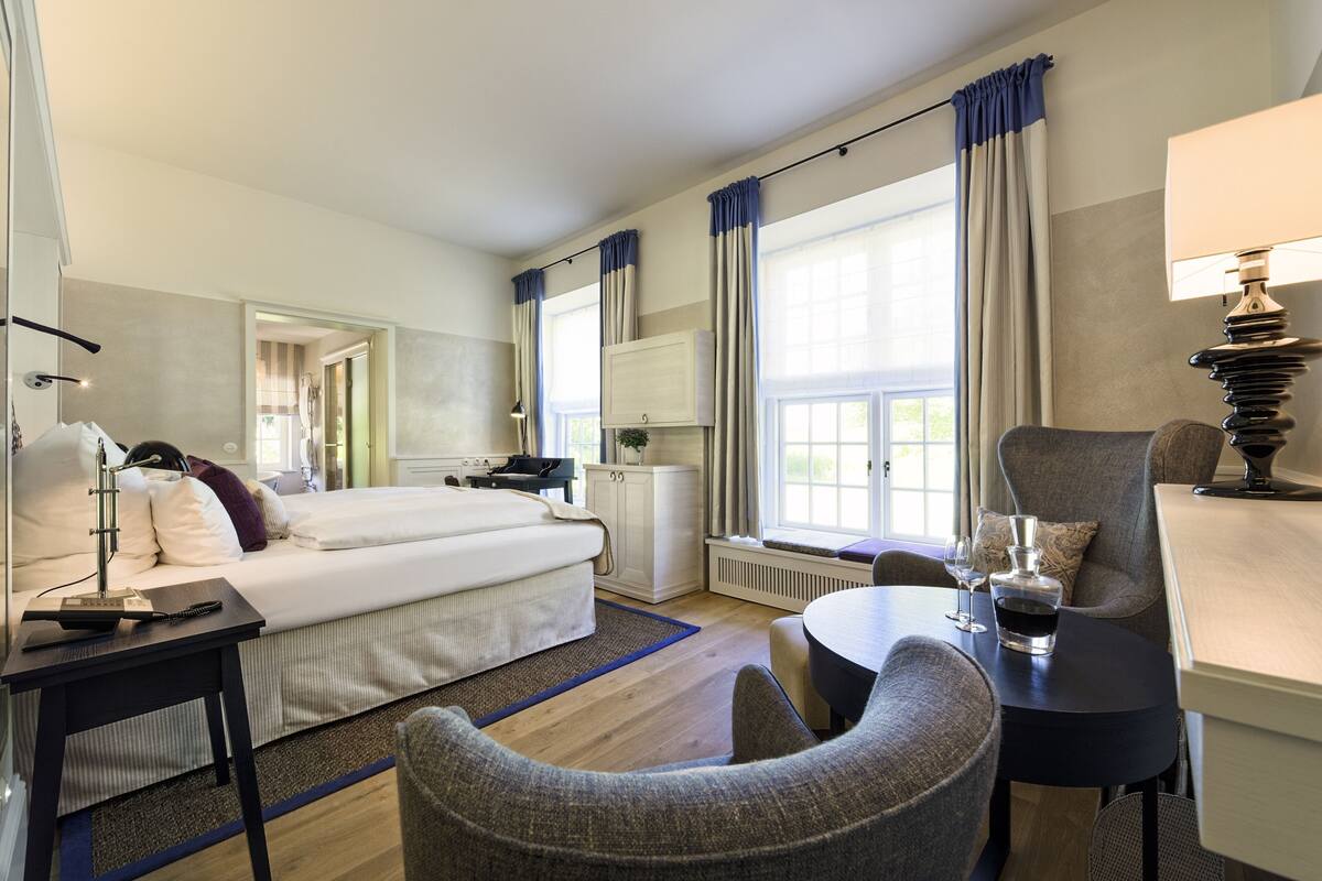 Une chambre d’hôtel avec un lit, un bureau, une chaise, une table et une lampe.