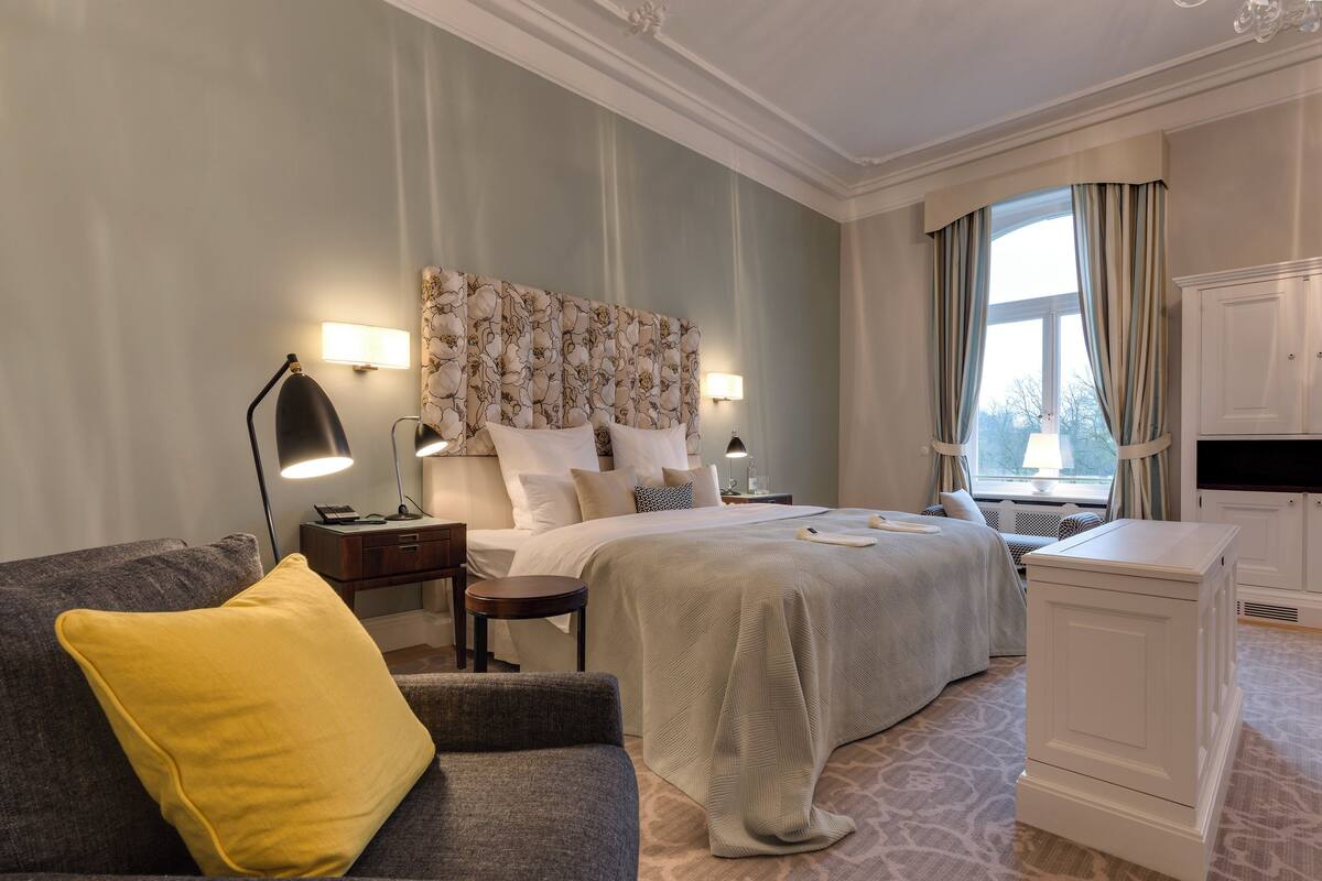 Une chambre d’hôtel avec un grand lit, un bureau, un canapé et une table de chevet avec des lampes.