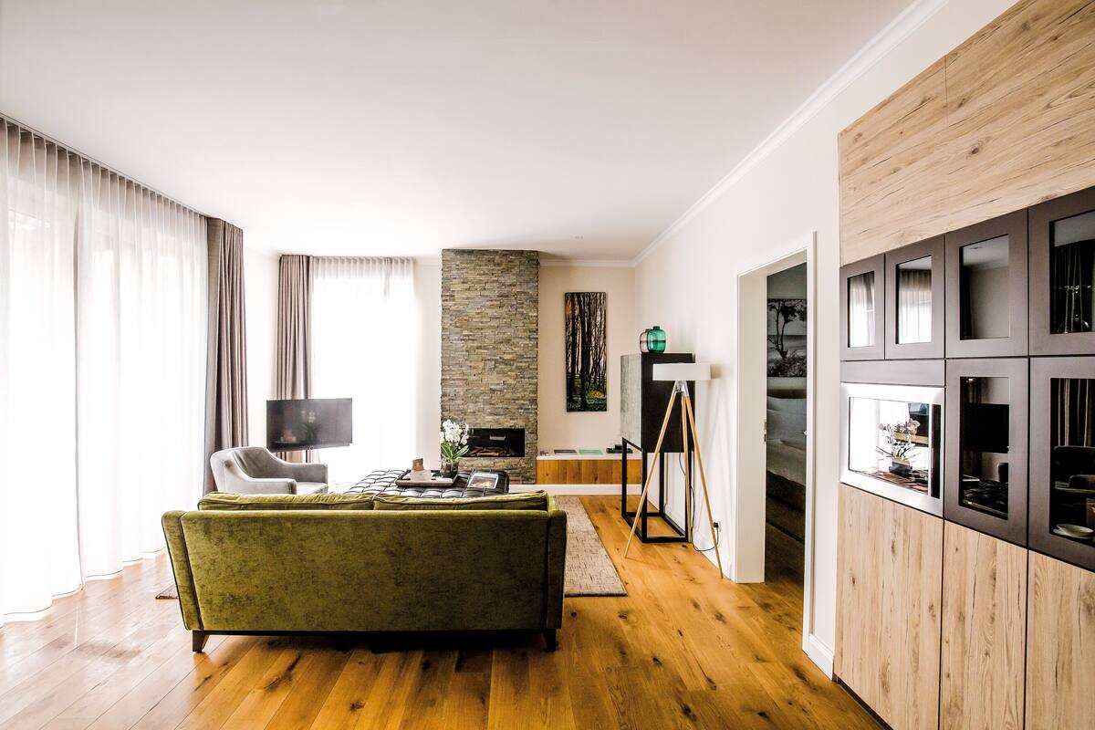 Un salon moderne avec un canapé vert, un téléviseur et une cheminée en pierre.