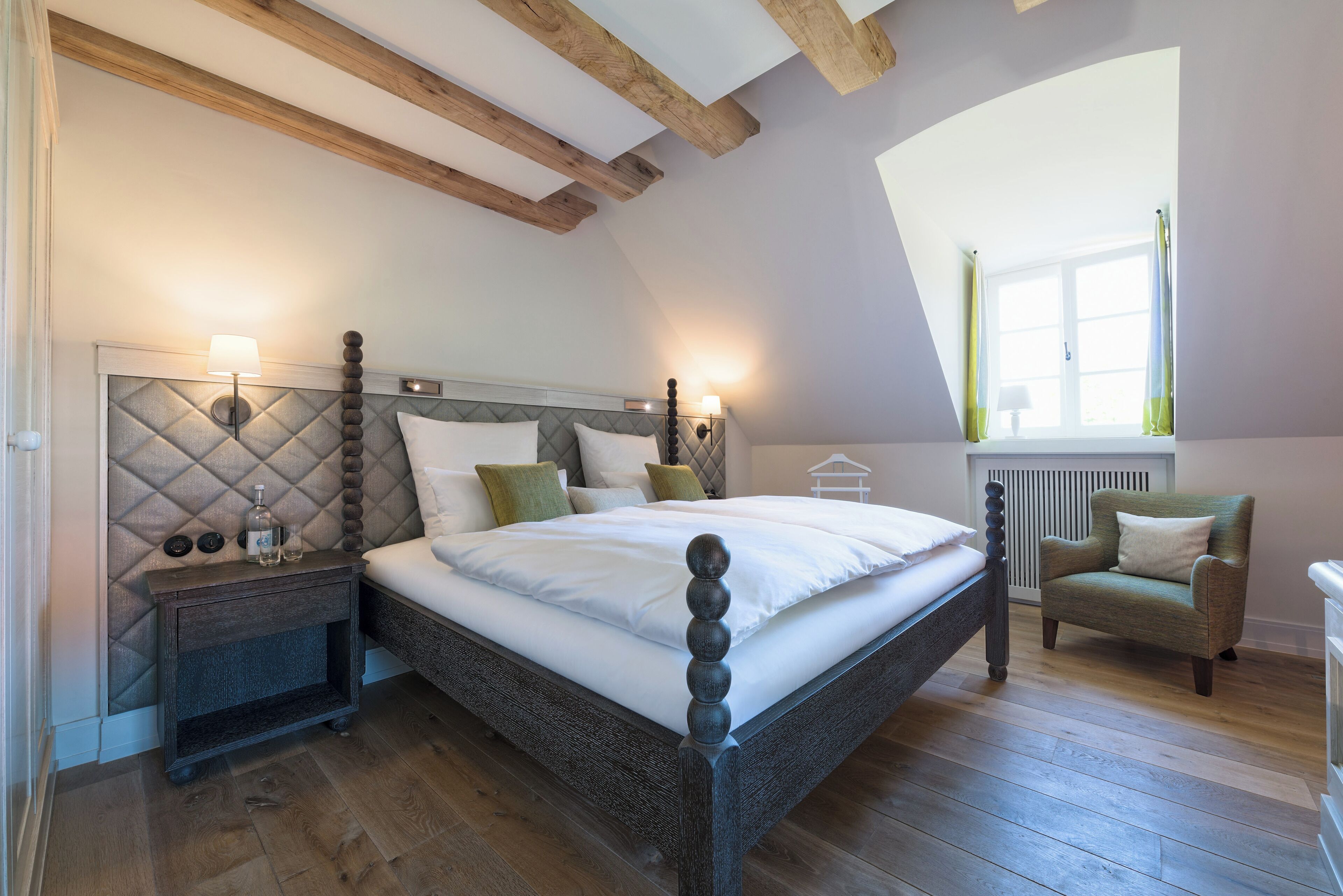 Une chambre à coucher avec un lit, des tables de chevet, une chaise et une fenêtre.