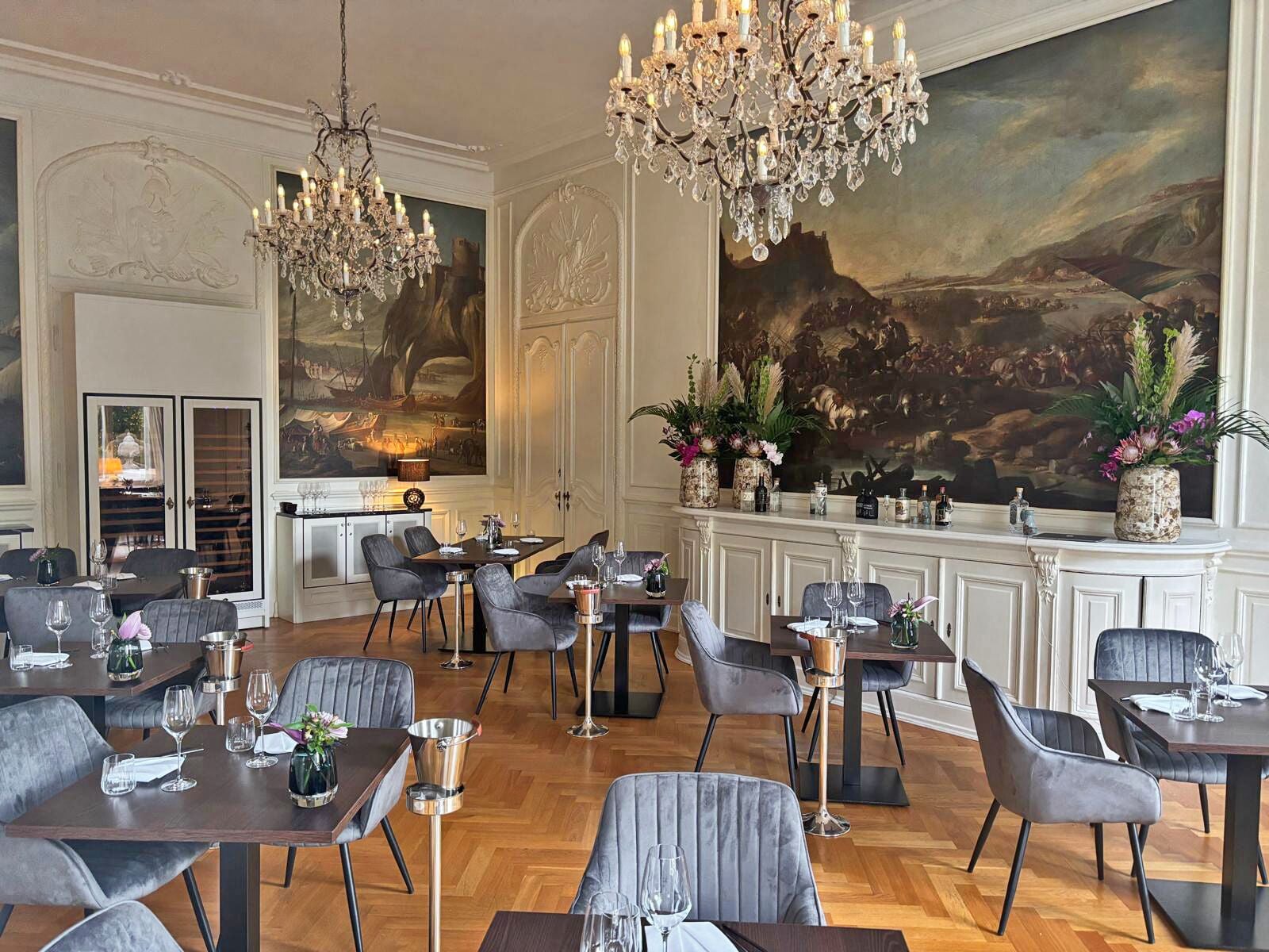 A dining area with multiple tables, chairs, and a large painting on the wall.