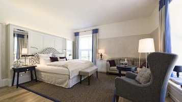 Una habitación de hotel con una cama grande, una silla, una mesita y una ventana con cortinas.