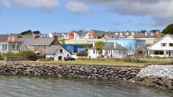 A coastal town with houses and a blue building, likely a hotel, by the water.