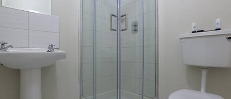 A bathroom with a glass-enclosed shower, a white sink, and a toilet.