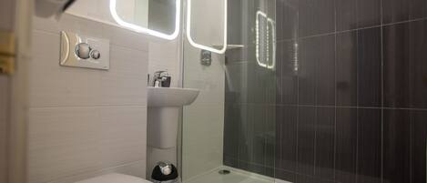 Un baño moderno con inodoro, lavamanos y ducha de vidrio.