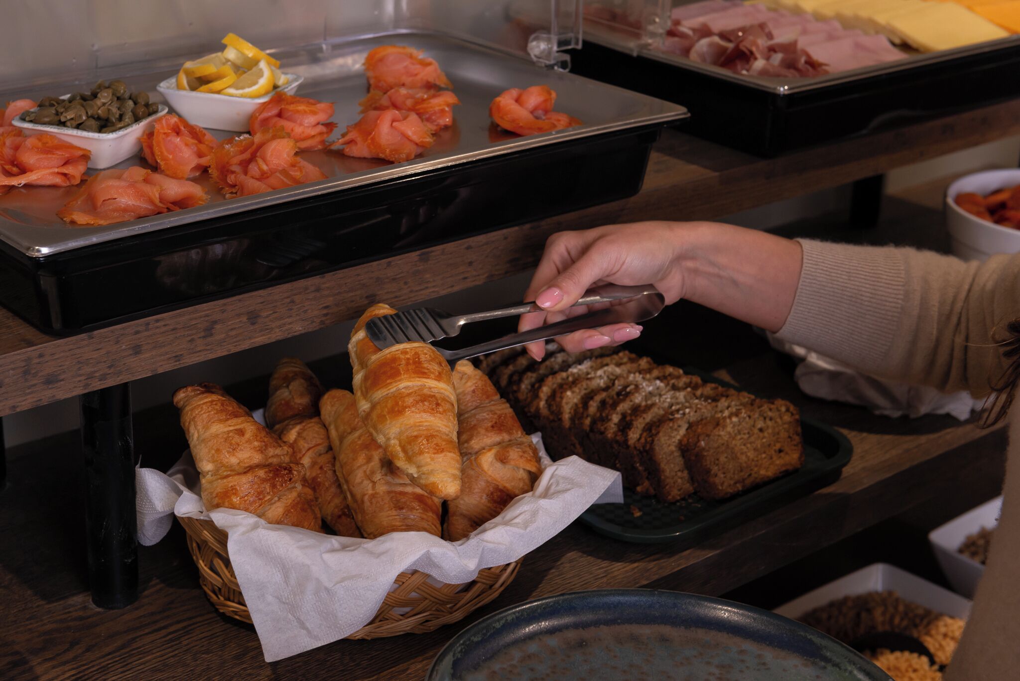 A buffet with various food items including salmon, bread, and pastries.