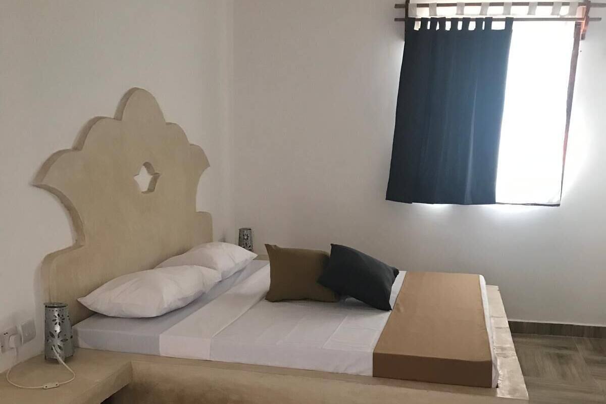 A bedroom with a bed, bedside table, and a window with curtains.