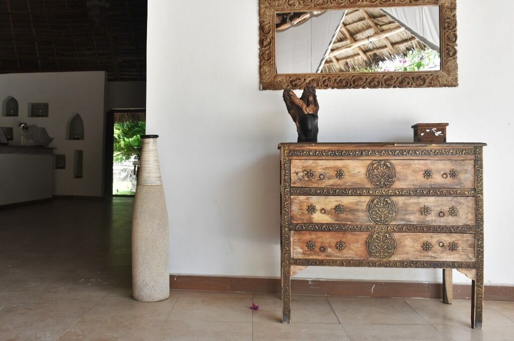 Un aparador de madera con tallas elaboradas y un espejo encima.