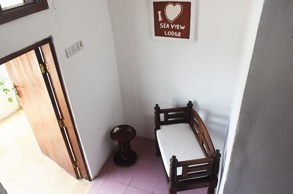 Une petite pièce avec un lit en bois, une petite table ronde et une pancarte au mur sur laquelle on peut lire : « J’adore ce chalet avec vue sur la mer ».