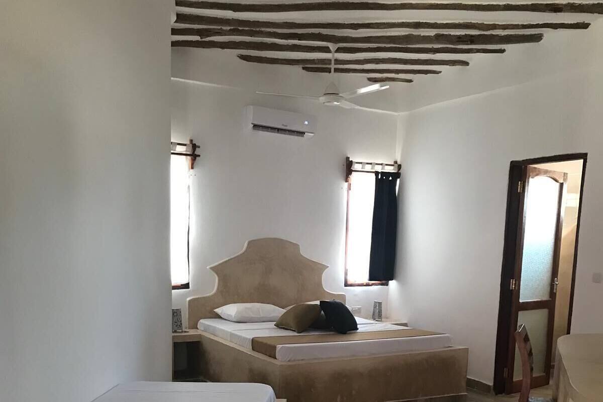 A room with a bed, a chair, a desk, and a ceiling fan.
