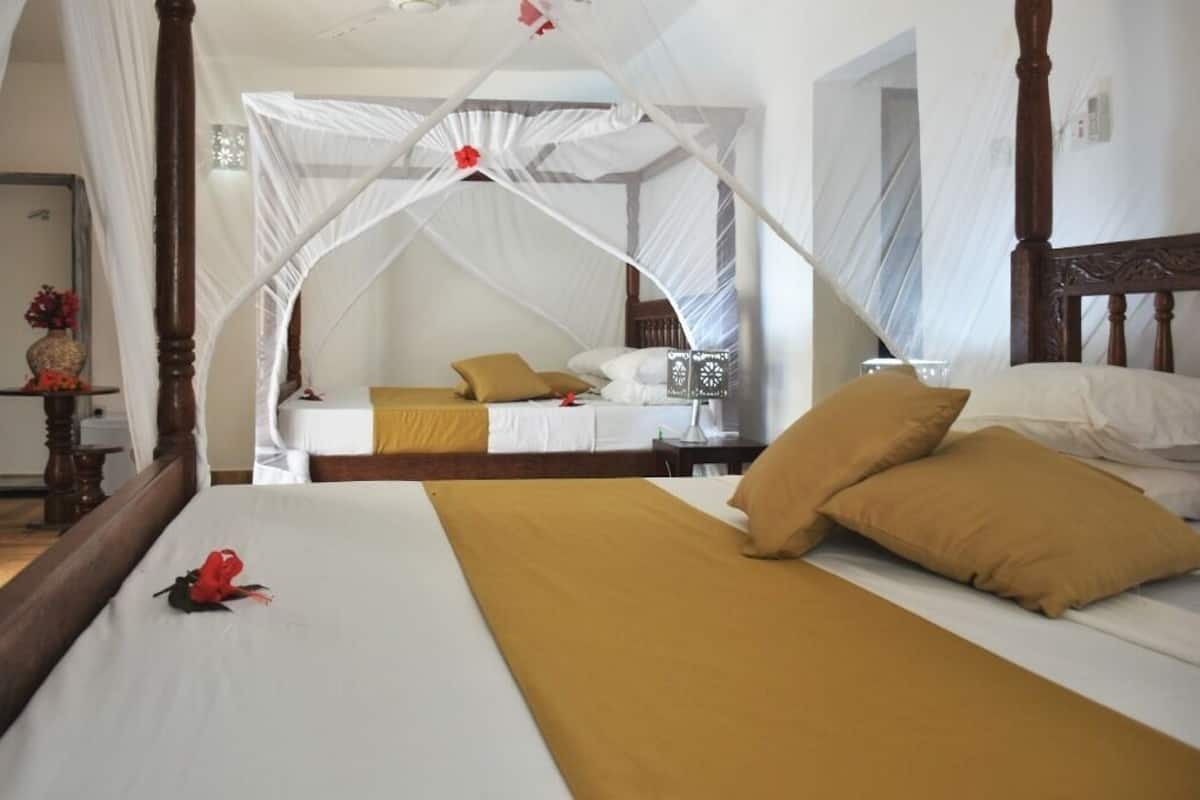A room with a large bed, a smaller bed, and a canopy bed.