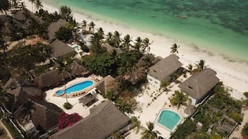 Relax in a pool surrounded by lush greenery and the soothing sound of the ocean.