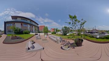 A modern outdoor patio with curved seating, planters, and a clear view of surrounding buildings.