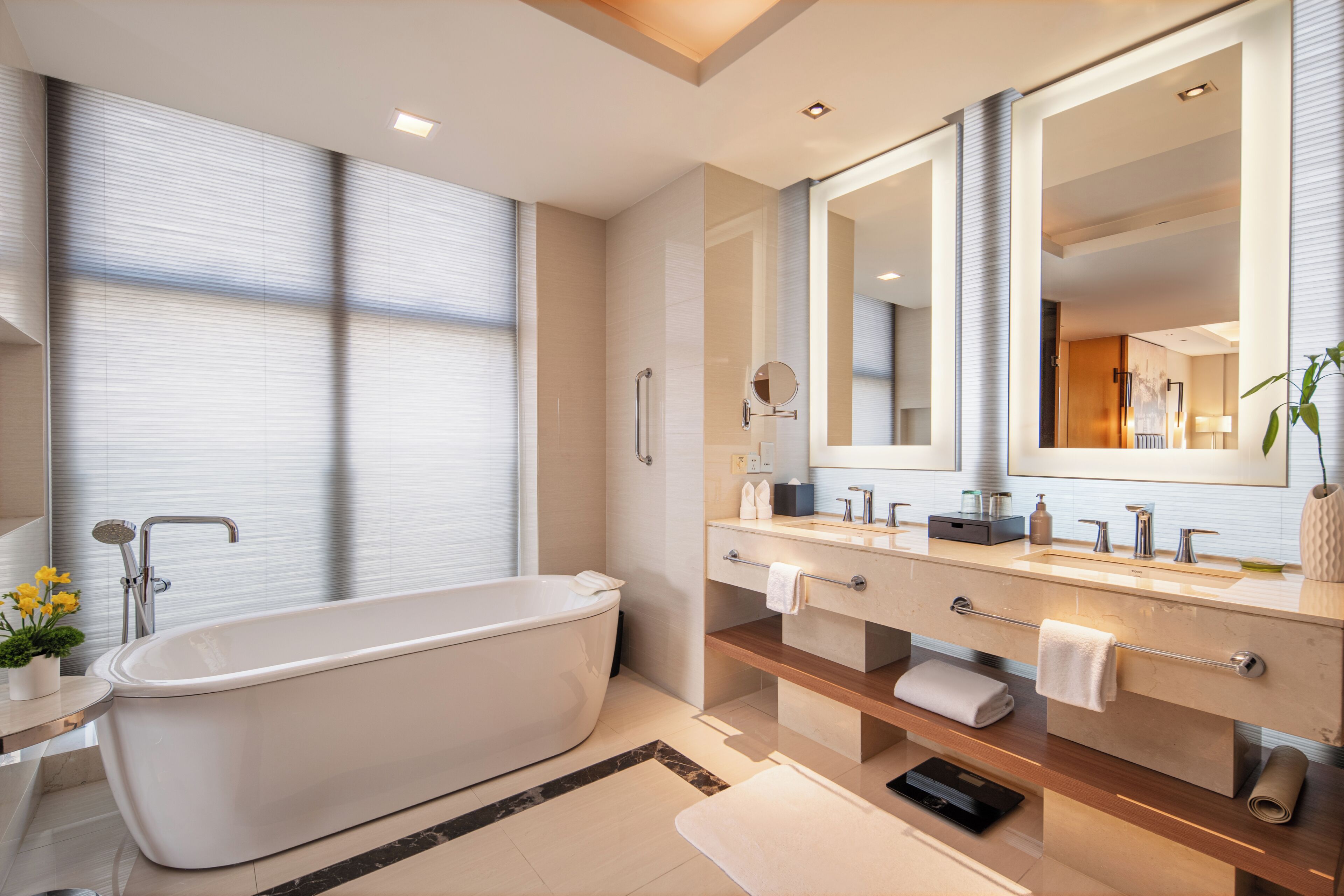 A modern bathroom with a freestanding bathtub, a large mirror, and a vanity with a double sink.