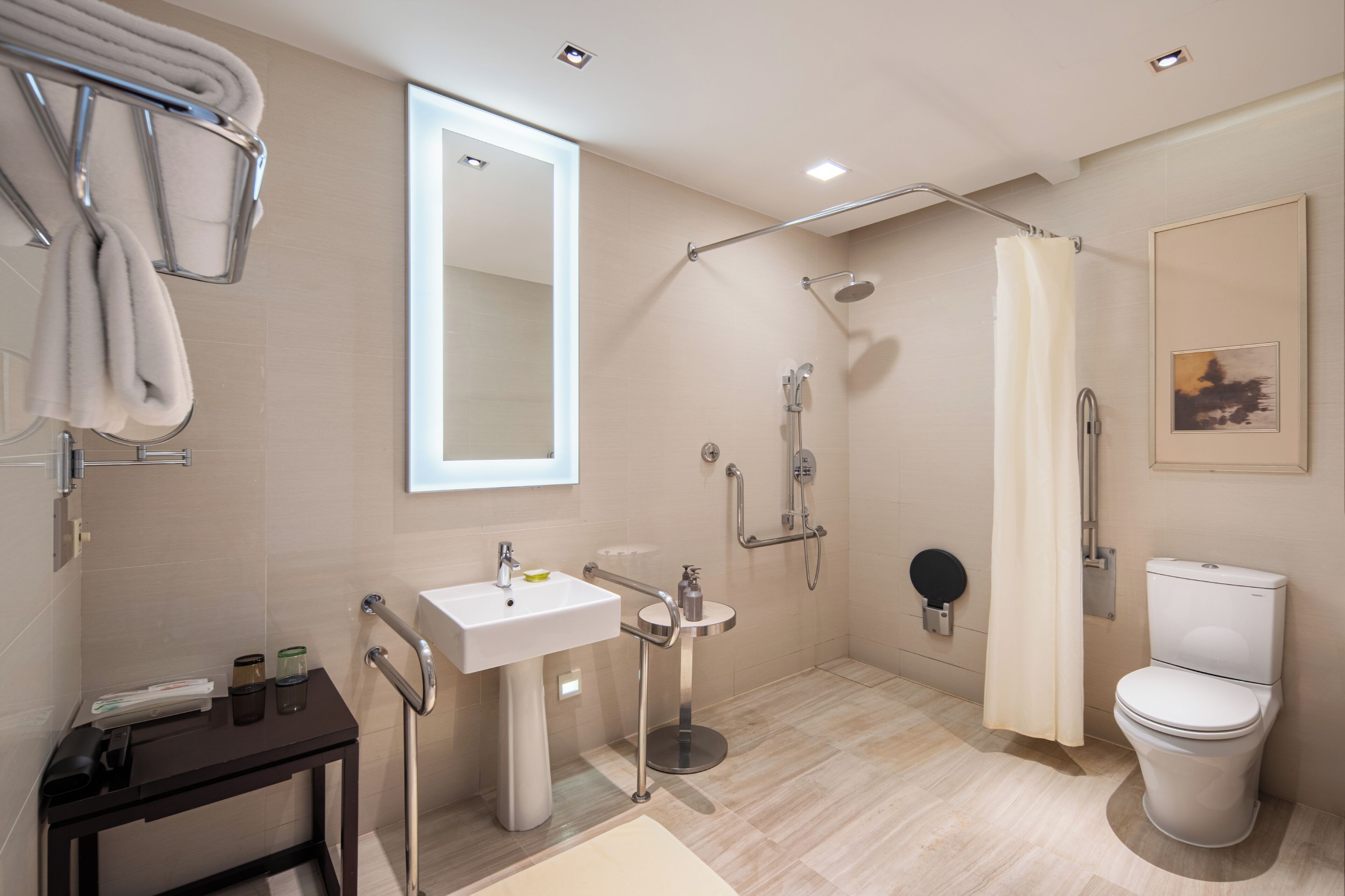 Een moderne badkamer met douche, toilet, wastafel en een handdoekhouder.