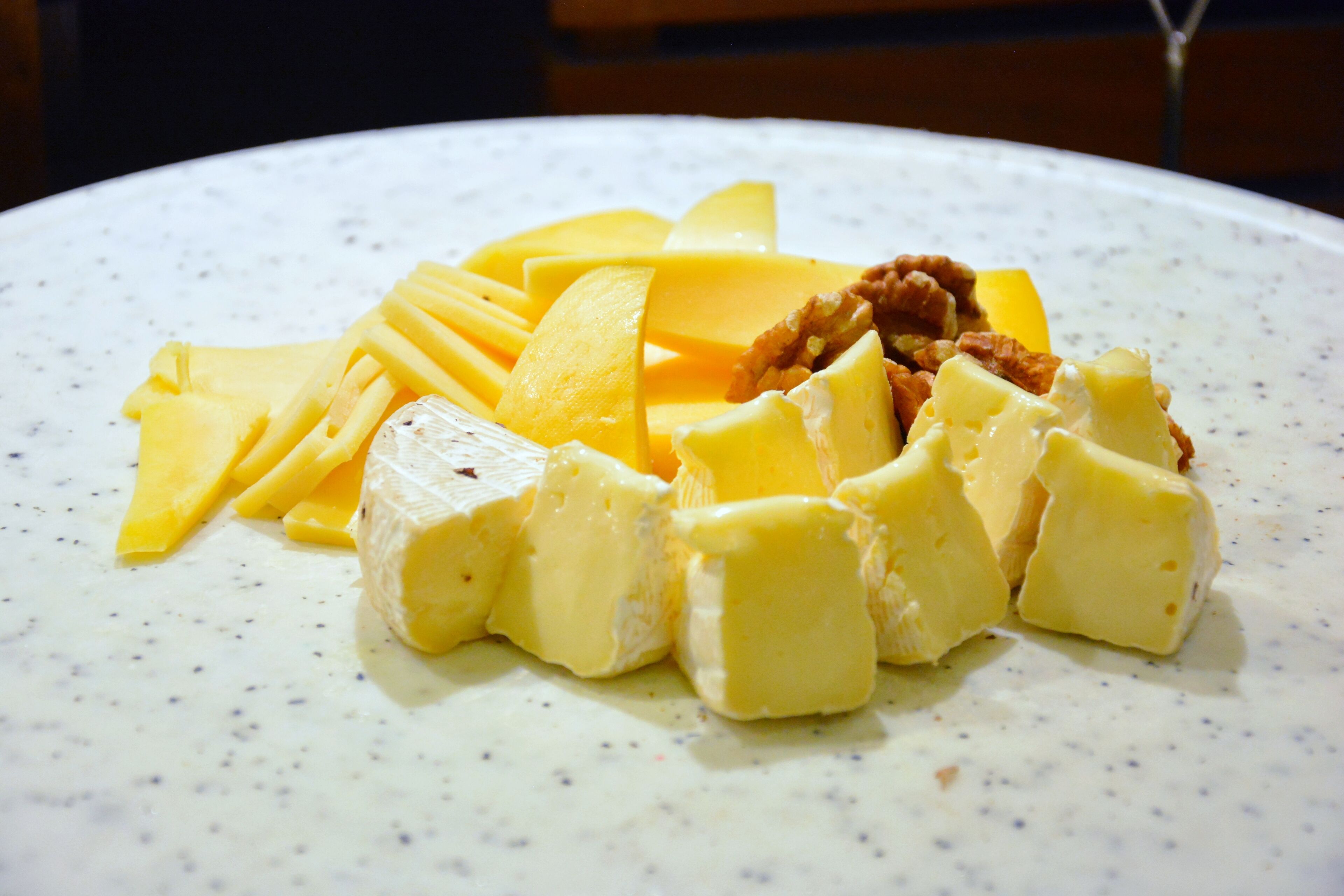 Un plato con diferentes quesos y nueces.